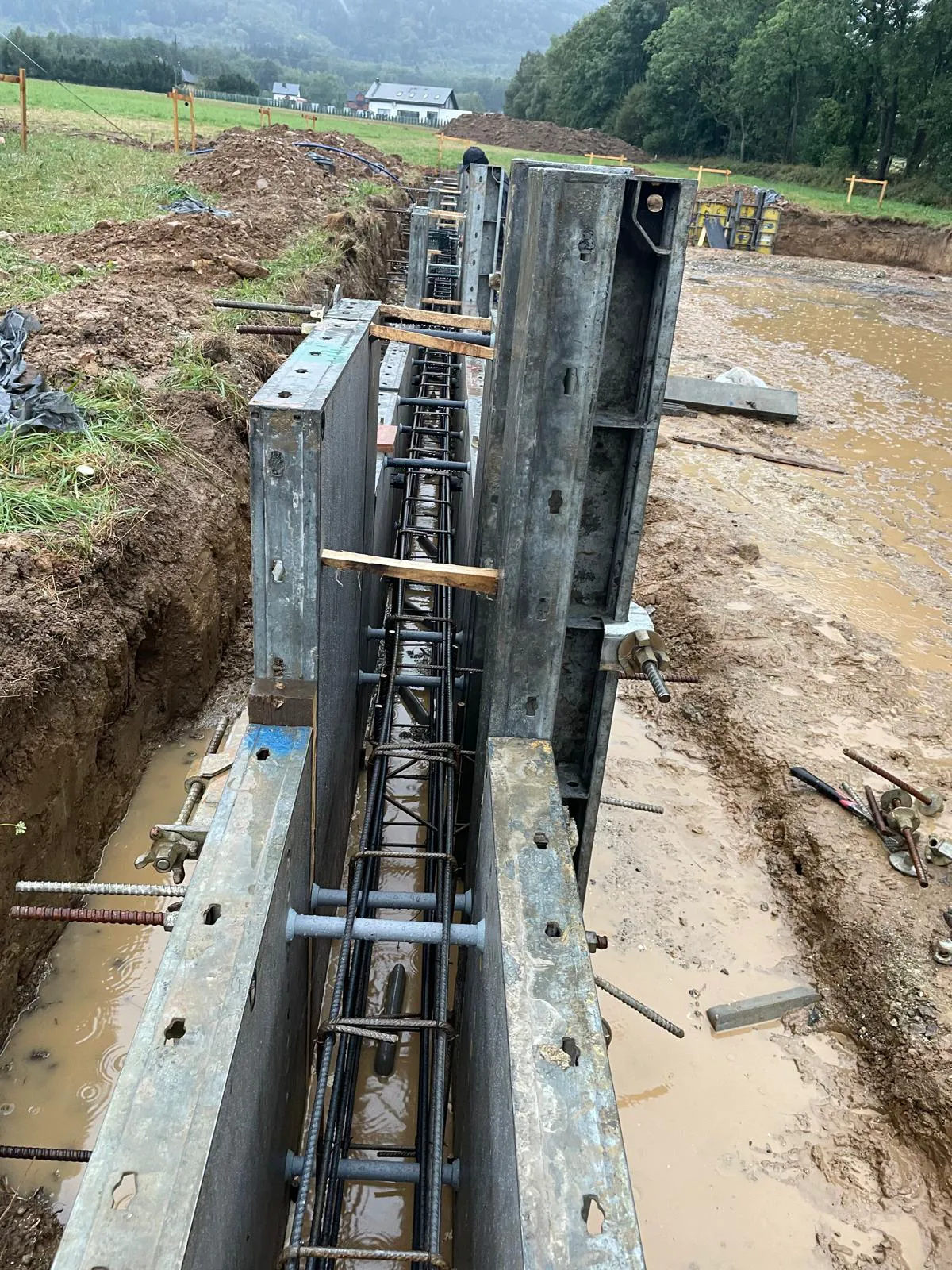 Formy szalunkowe z umocowanym zbrojeniem fundamentów w wykopie na placu budowy