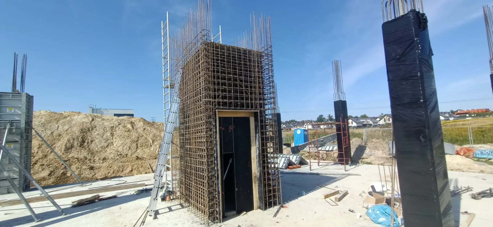 Roboty żelbetowe przy zbrojeniu słupa i szalunku na płycie fundamentowej na placu budowy