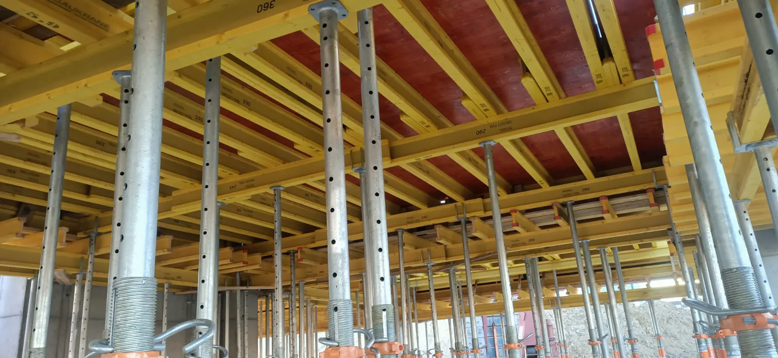 Montaż systemowych podpór i żółtych belek deskowania pod strop betonowy – Stropy