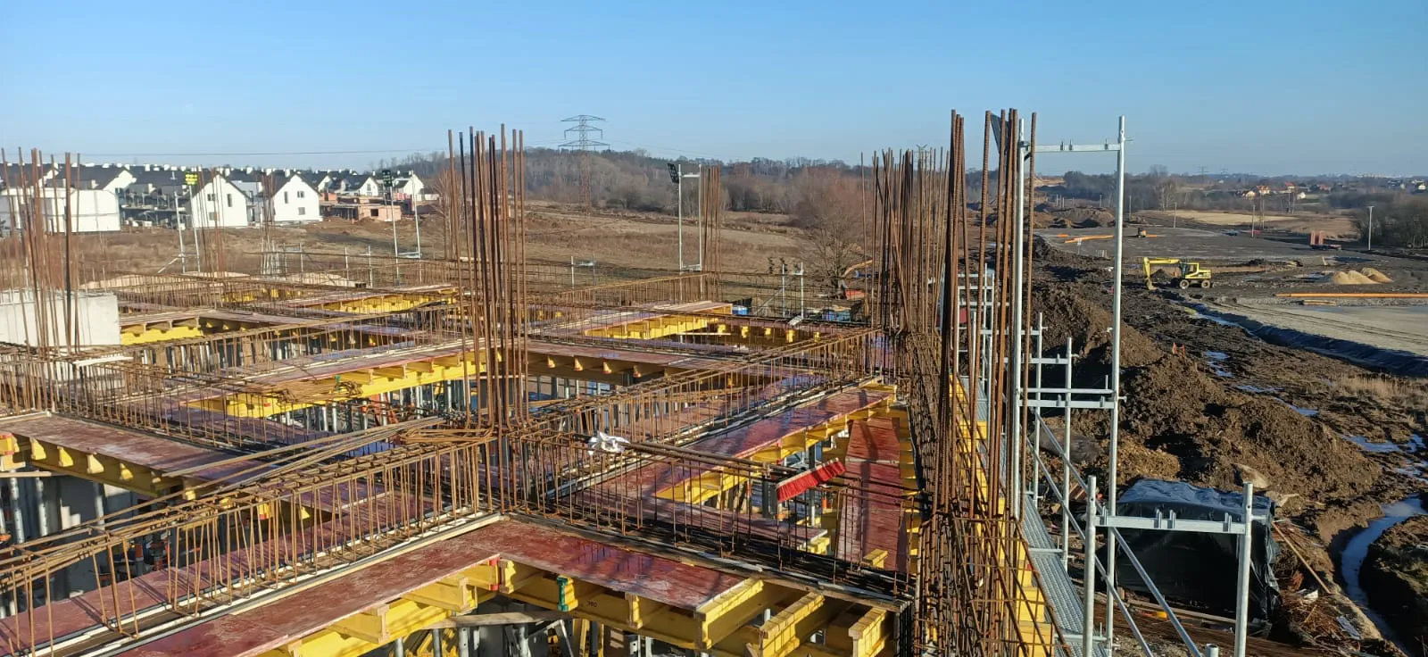 Roboty żelbetowe: zbrojenie słupów i stropu z deskowaniem na fundamentach w trakcie budowy domu