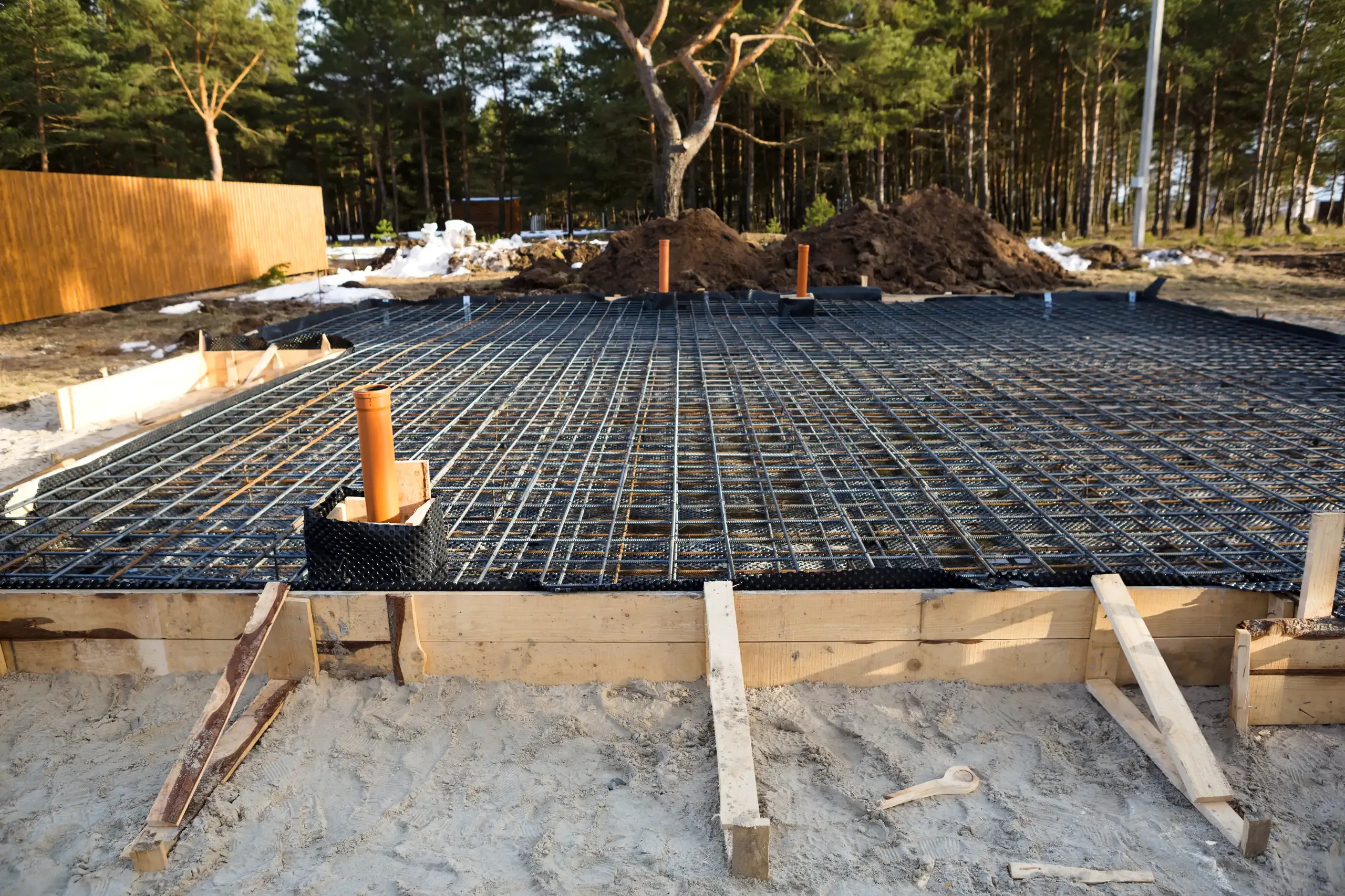 Zbrojona siatką stalową płyta fundamentowa z przygotowanymi przepustami rurowymi na budowie