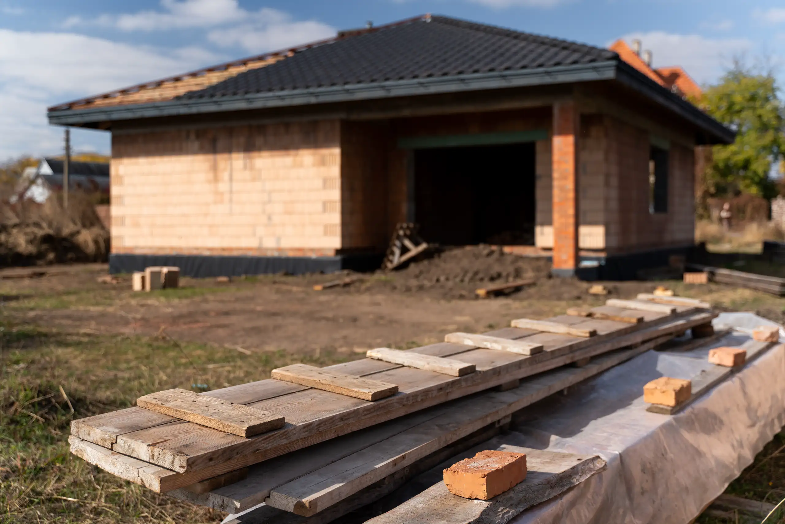 Dom w stanie surowym zamkniętym z ceglaną konstrukcją i deskami na pierwszym planie